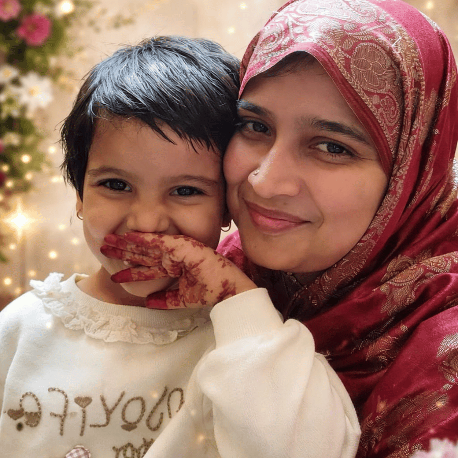 Mother and baby girl smiling together in a warm festive setting wearing traditional outfit, representing love and comfort in Sigoor Fashion