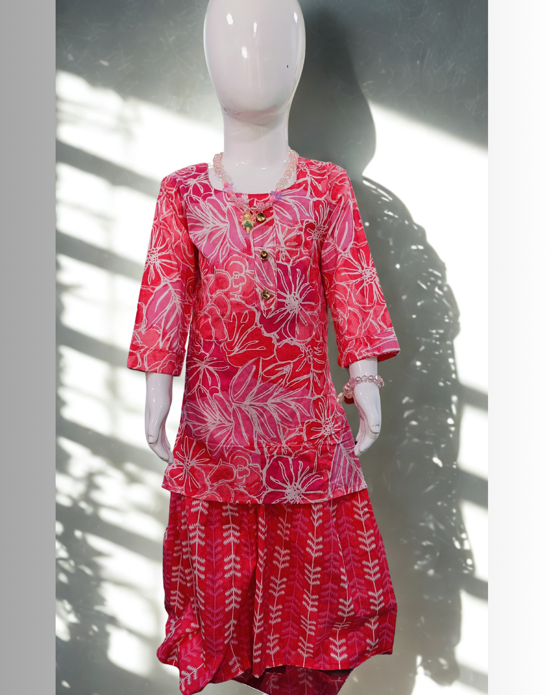 Gulfam baby girl kurti set, coral/salmon pink base, large white floral print, gold buttons, arrow-print palazzo - front view