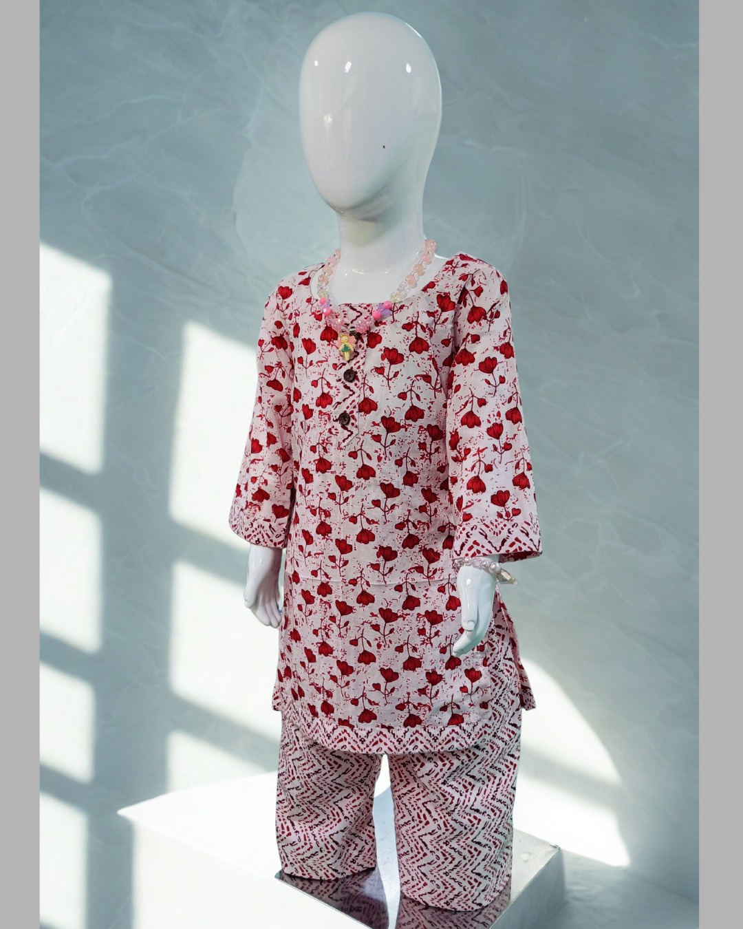 Khushboo baby girl kurti set, white base, red tulip print, 3 buttons, chevron borders, red chevron pants - front view