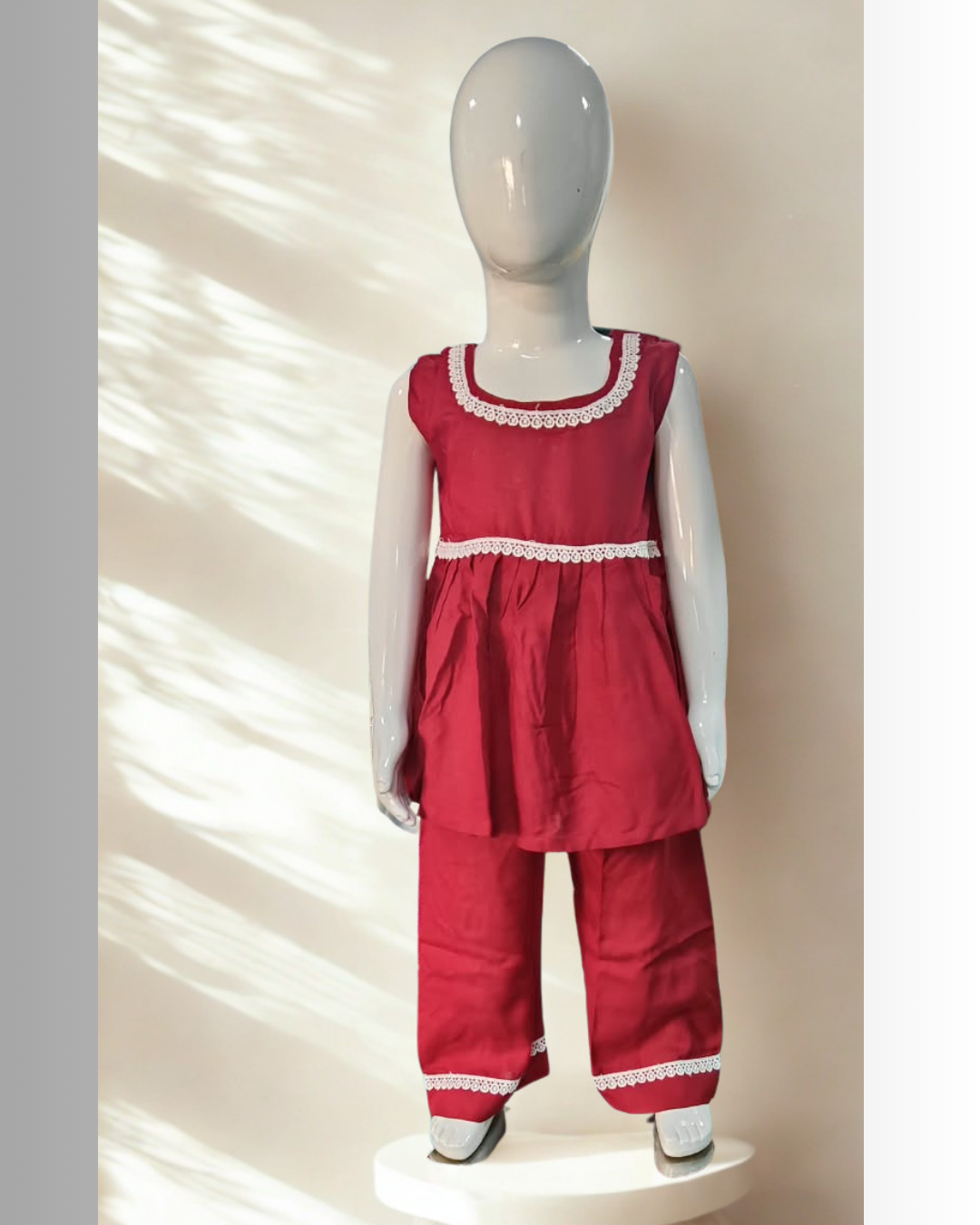 Laadli baby girl kurti set, crimson-maroon base, sleeveless, gathered waist, white lace on neckline, waist and pants hem - front view