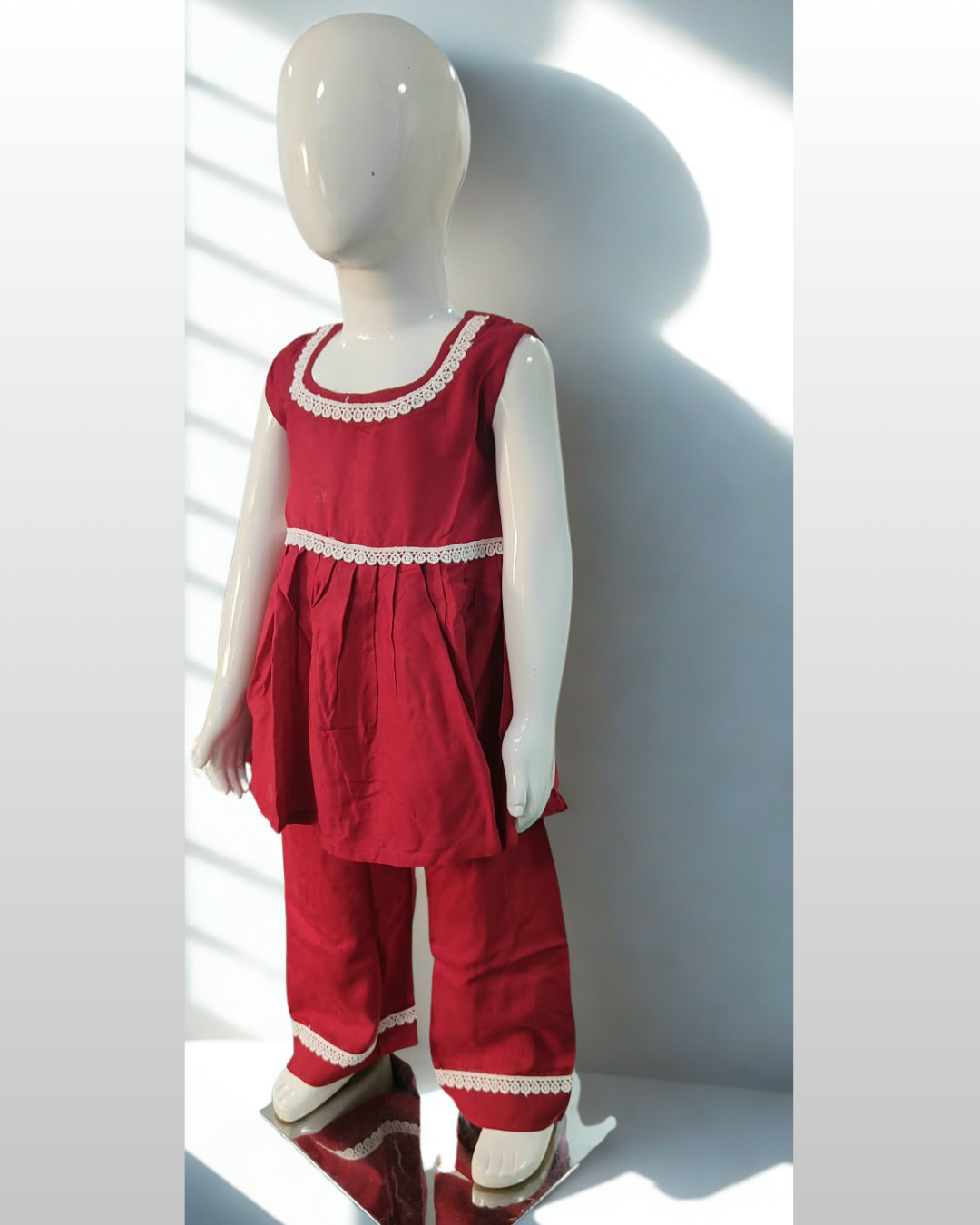 Laadli baby girl kurti set, crimson-maroon base, sleeveless, gathered waist, white lace on neckline, waist and pants hem - side view