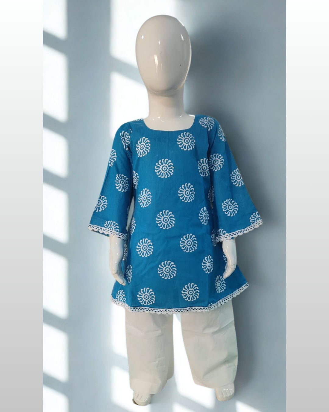 Roshni baby girl kurti set, blue base, white sun-motif print, square neckline, bell sleeves, white lace trim, white pants - front view
