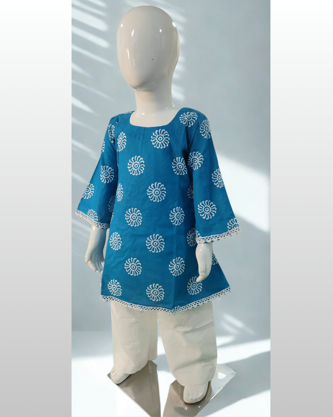 Roshni baby girl kurti set, blue base, white sun-motif print, square neckline, bell sleeves, white lace trim, white pants - side view