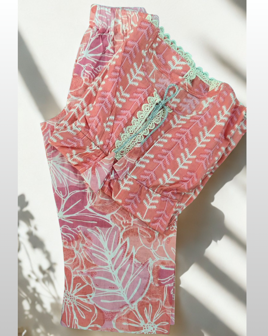 Sawera baby girl kurti set, bright pink kaftan style, white fern print, silver cord tie neckline, cream lace edges, floral-print pants - folded
