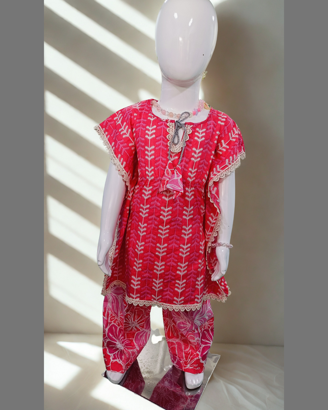Sawera baby girl kurti set, bright pink kaftan style, white fern print, silver cord tie neckline, cream lace edges, floral-print pants - front view
