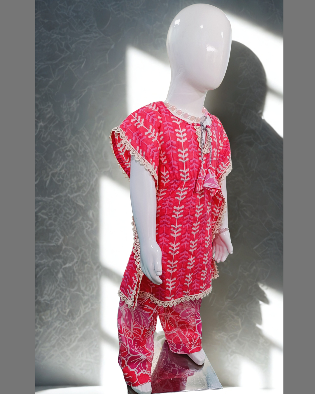 Sawera baby girl kurti set, bright pink kaftan style, white fern print, silver cord tie neckline, cream lace edges, floral-print pants - side view