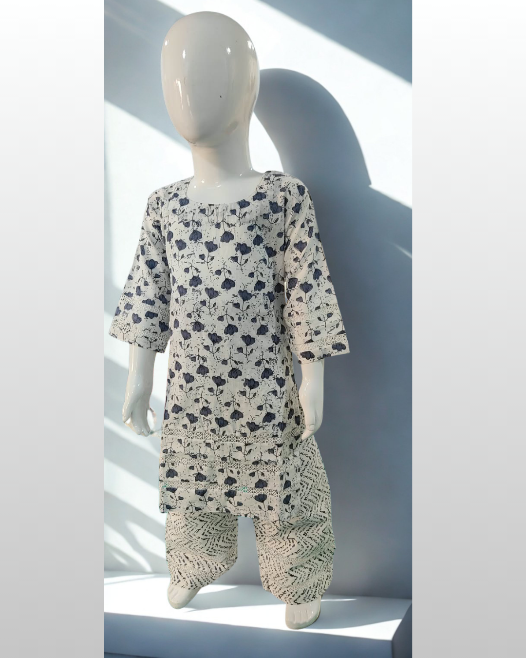 Shabana baby girl kurti set, white base, grey tulip print, three rows of cutwork lace, lace sleeve bands, grey chevron-print pants - front view