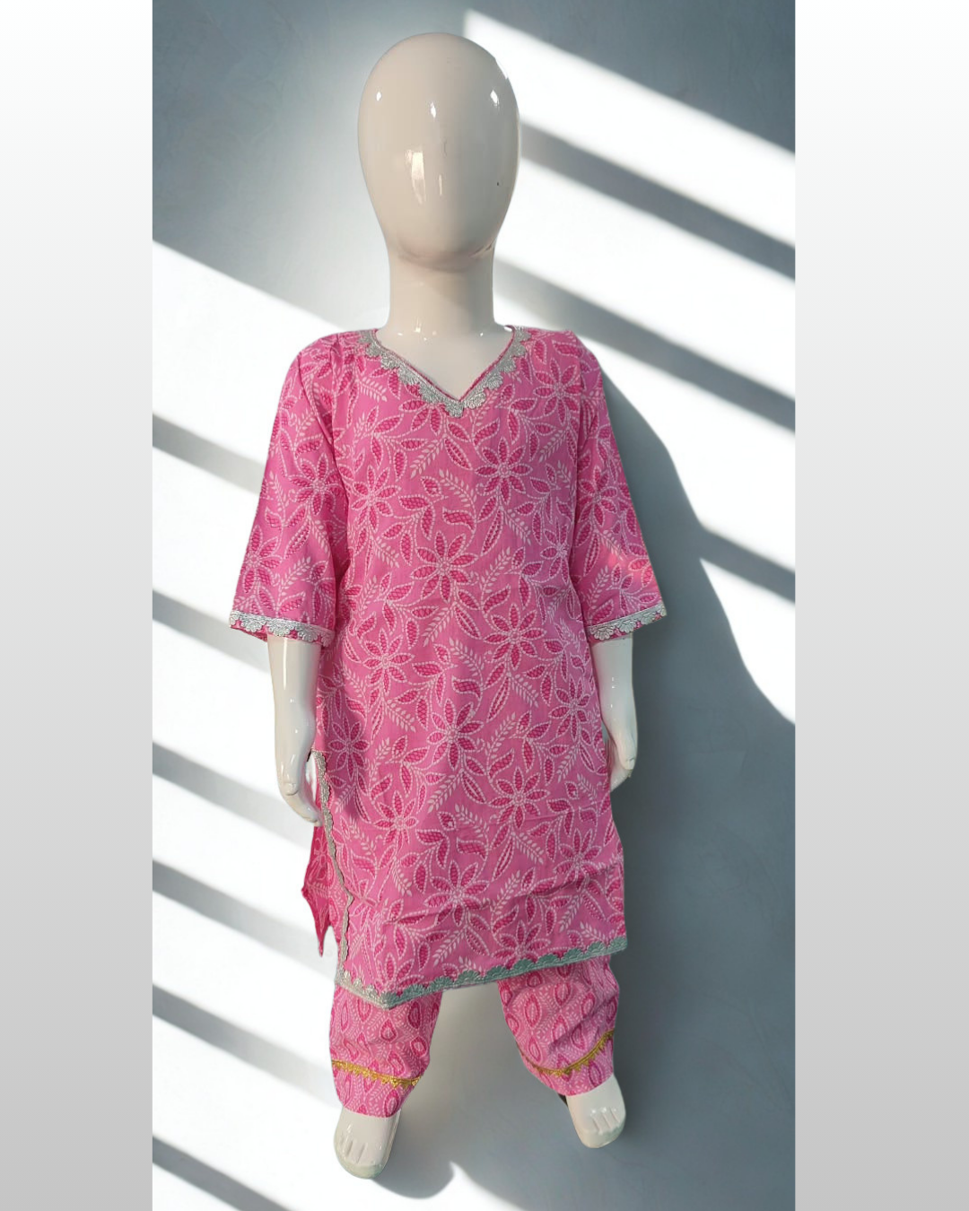 Yasmeen baby girl kurti set, soft pink base, white leaf-floral print, silver gota lace on V-neckline, sleeves and hem, oval-print pants - front view