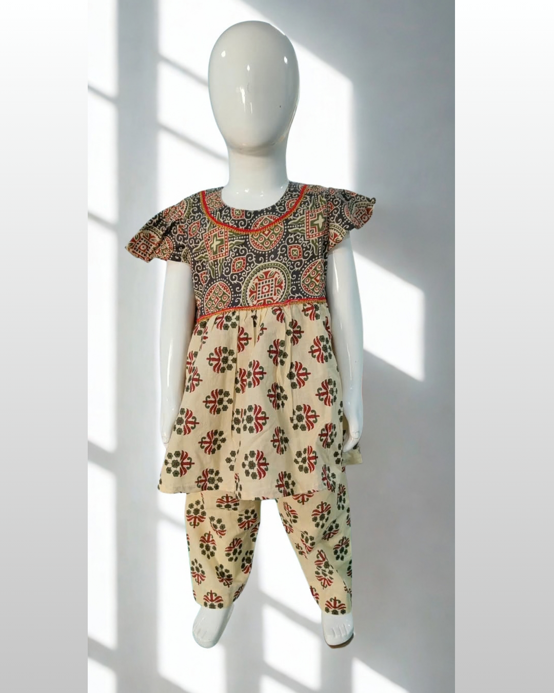 Zardozi baby girl kurti set, black base, bold ajrakh paisley print, red neckline trim - front view